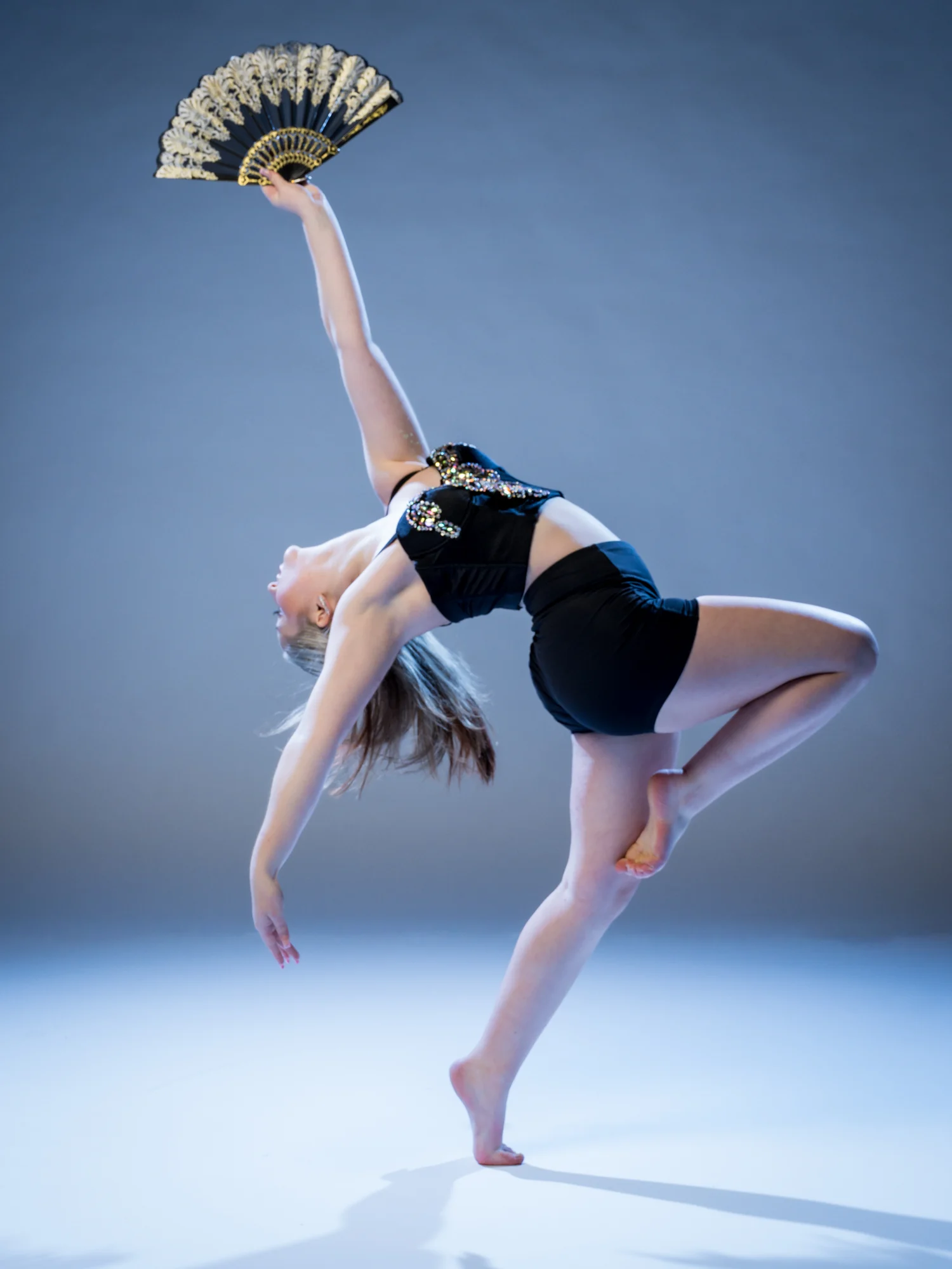 Aubry Travis mid-dance, back arched, holding a folding fan overhead